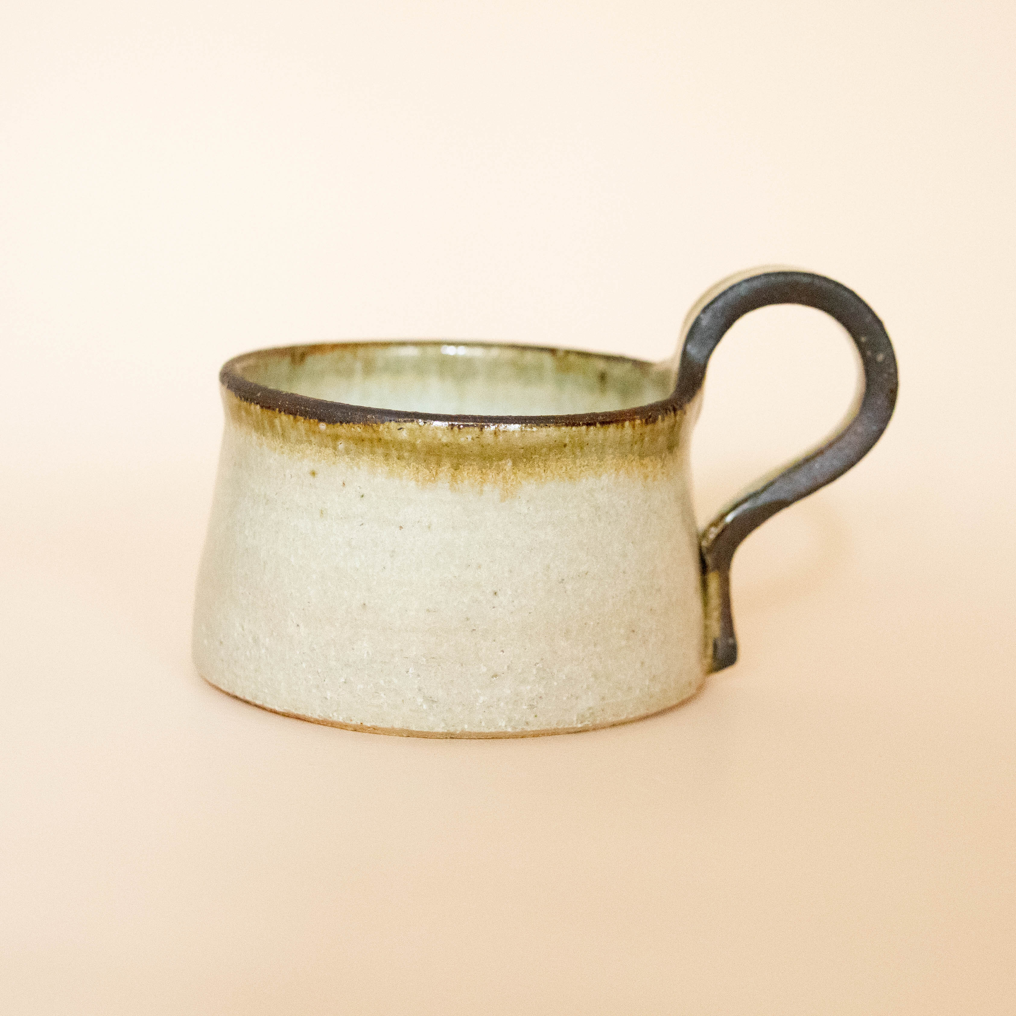 Rustic cup with brown rim and handle