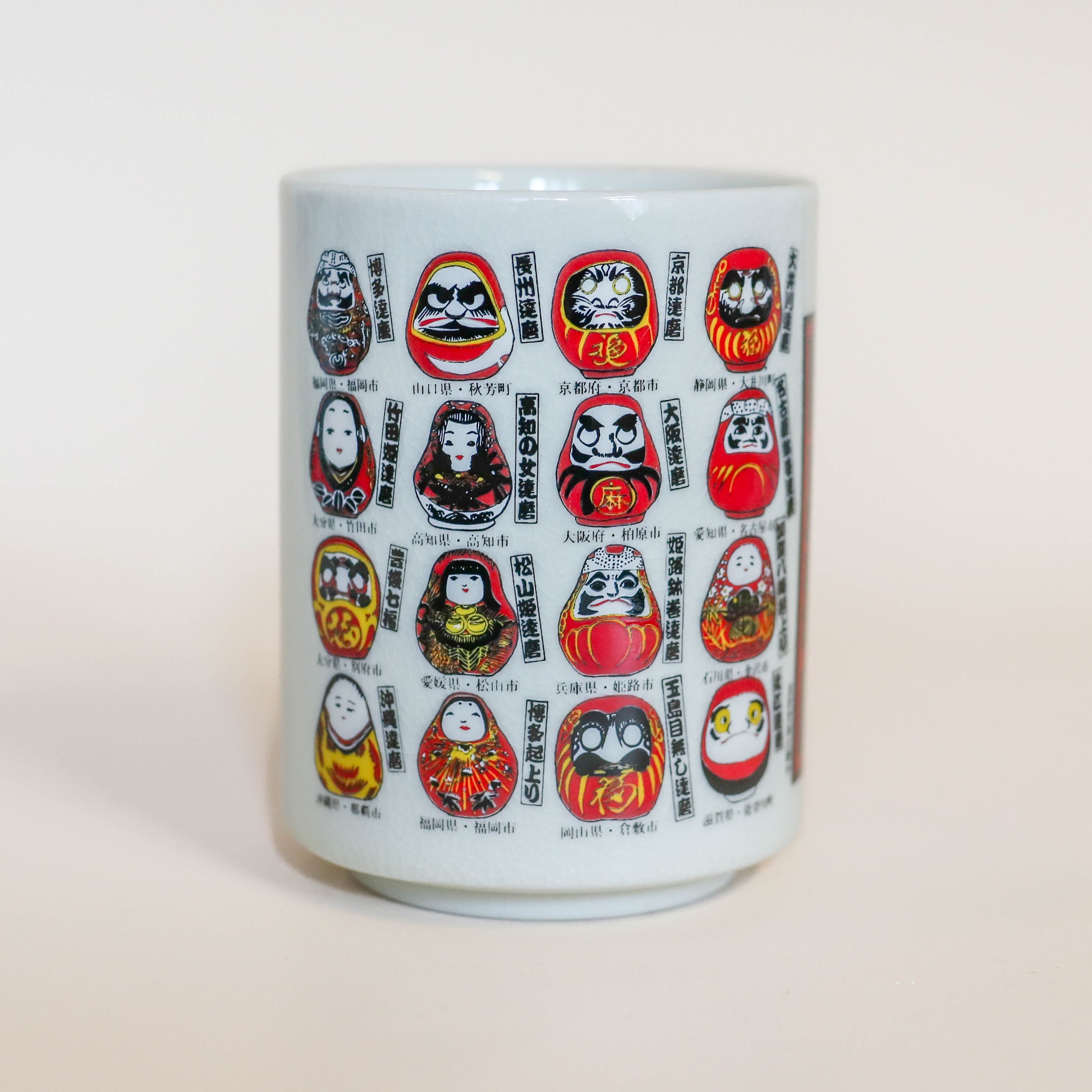 Kop med små daruma figurer i forskellige designs