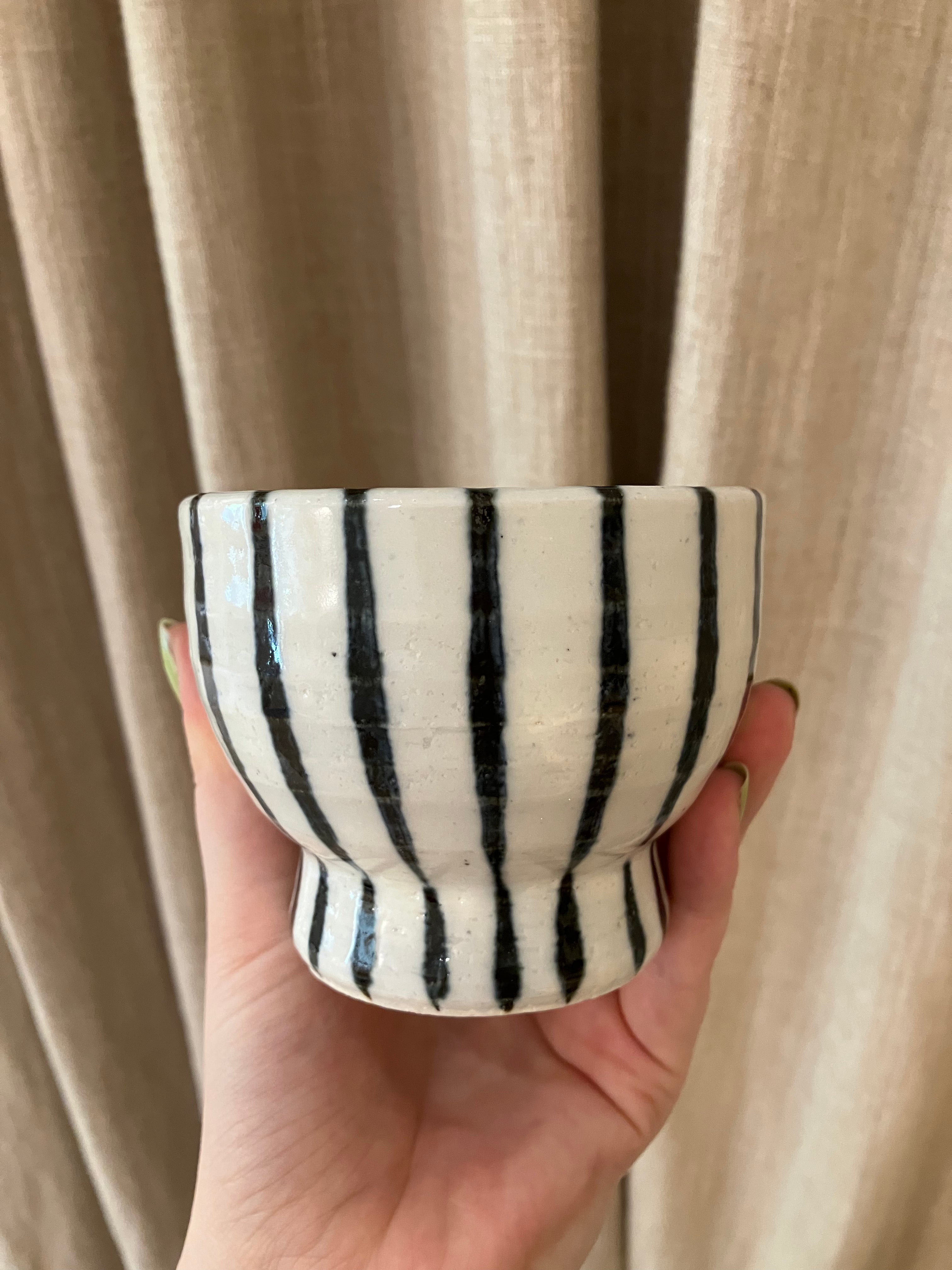 White ceramic cup on foot with dark blue stripes