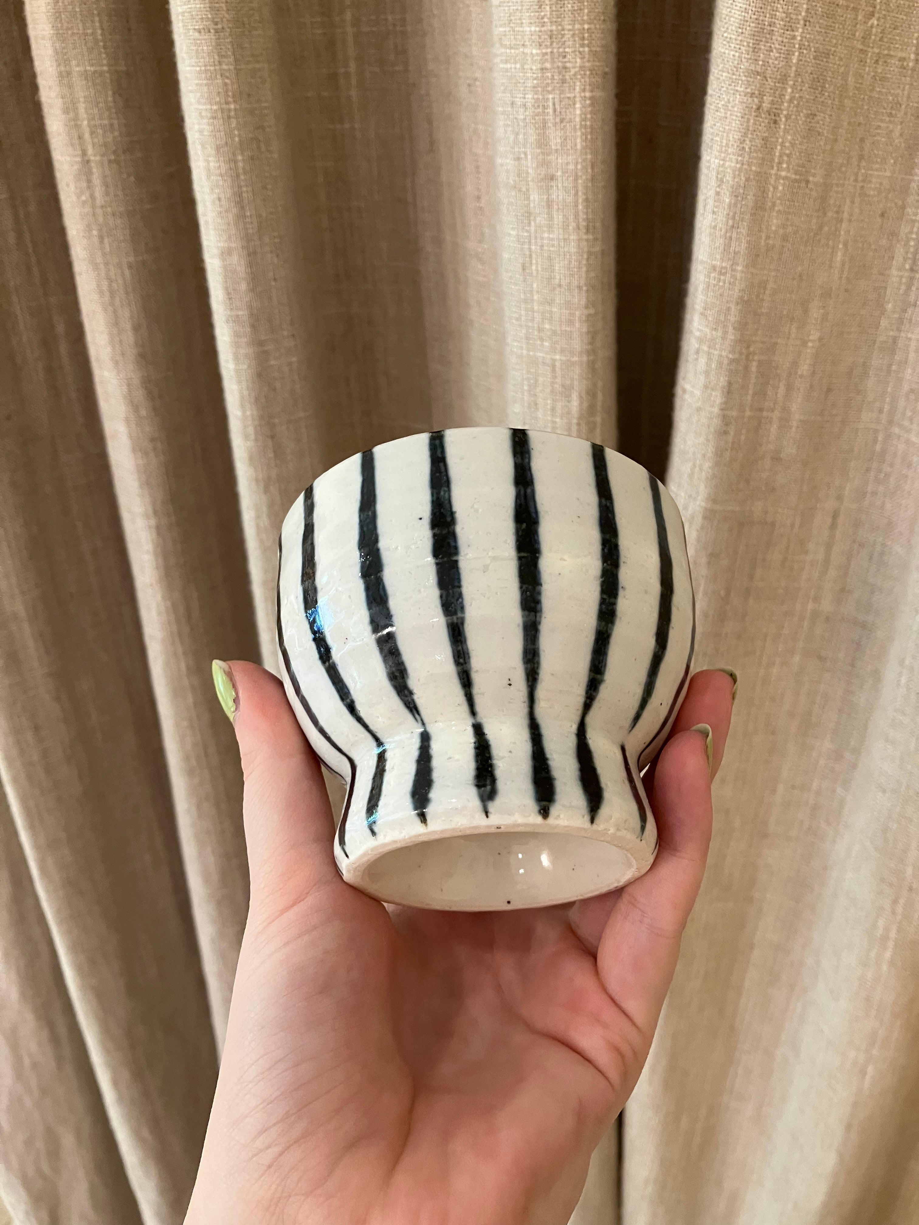 White ceramic cup on foot with dark blue stripes