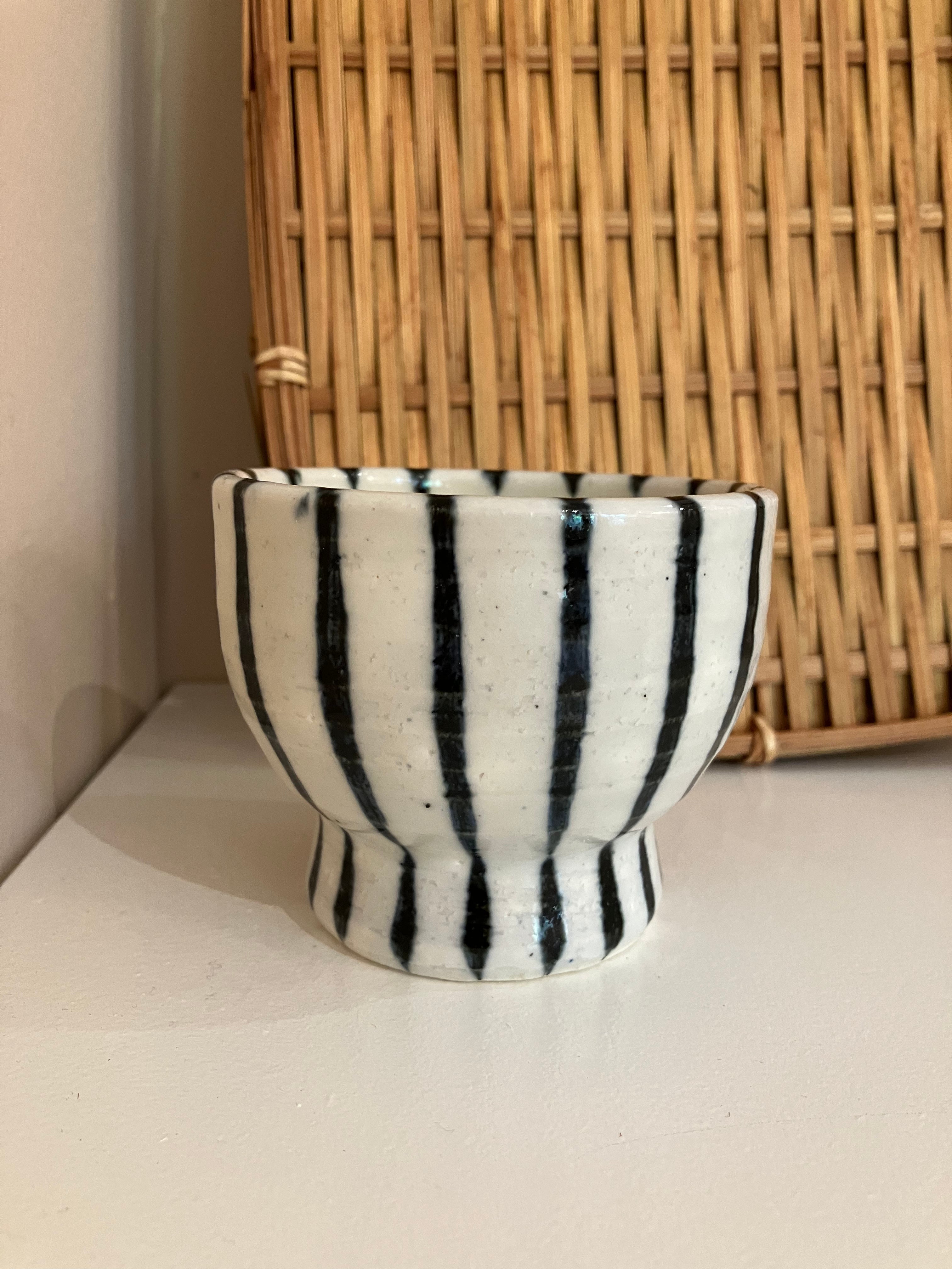 White ceramic cup on foot with dark blue stripes